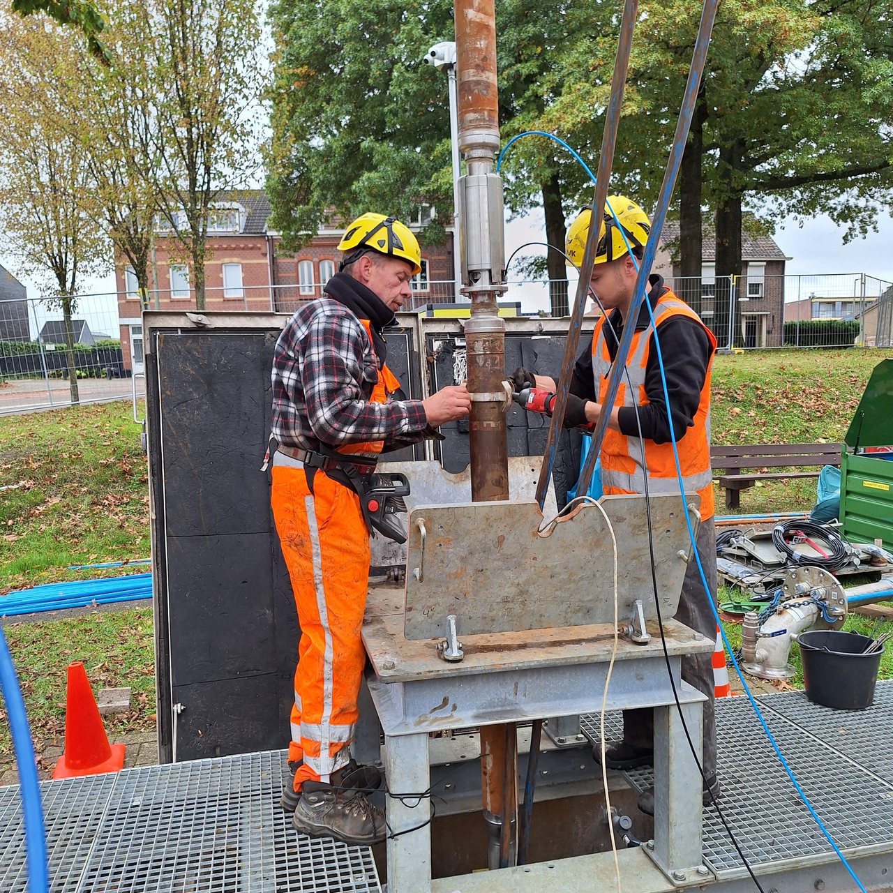 Twee technici monteren de stijgbuis met de 2½” klep boven de bronput bij Mijnwater in Heerlen